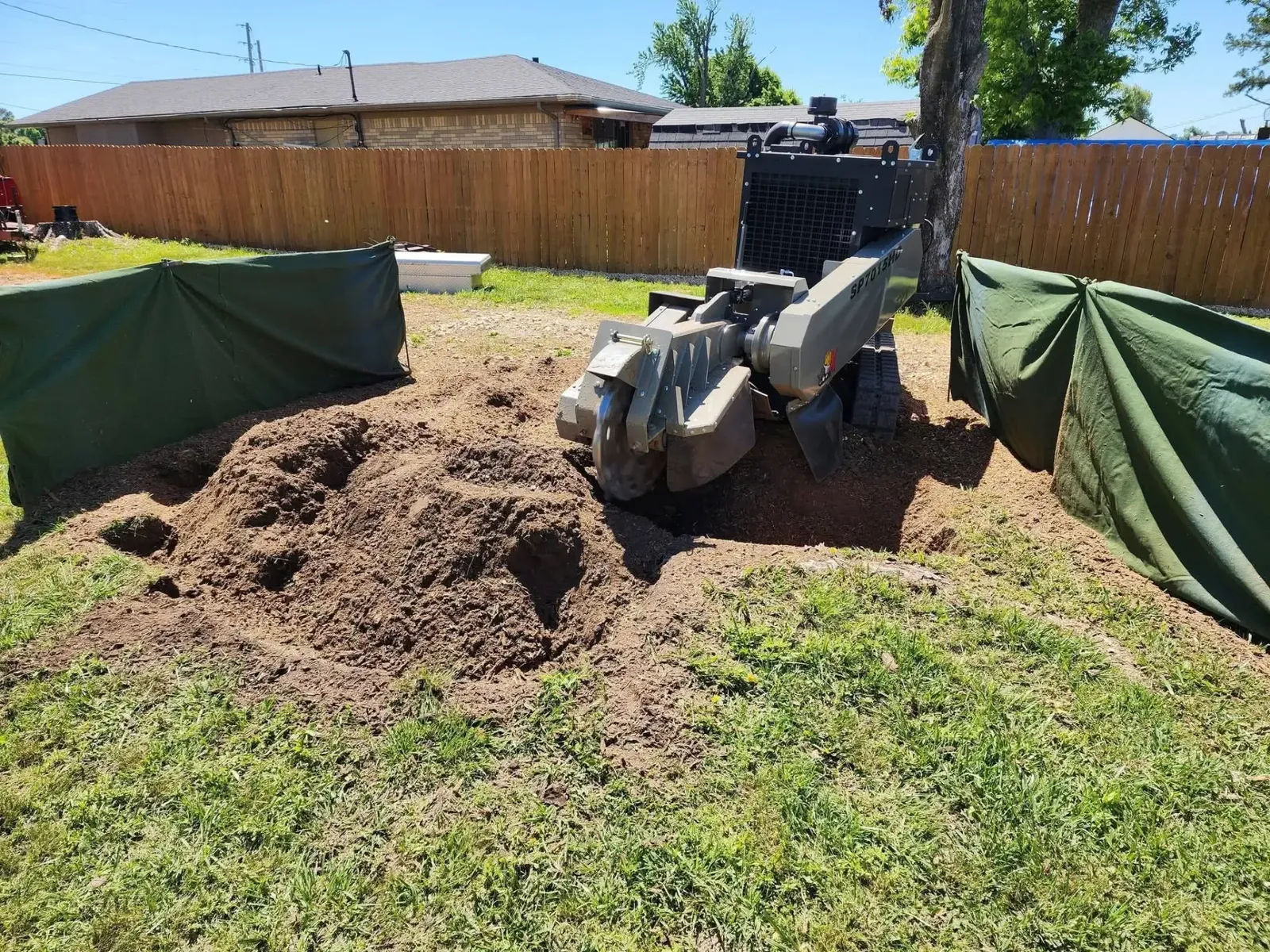 Stump grinding equipment with protective screens in a residential backyard